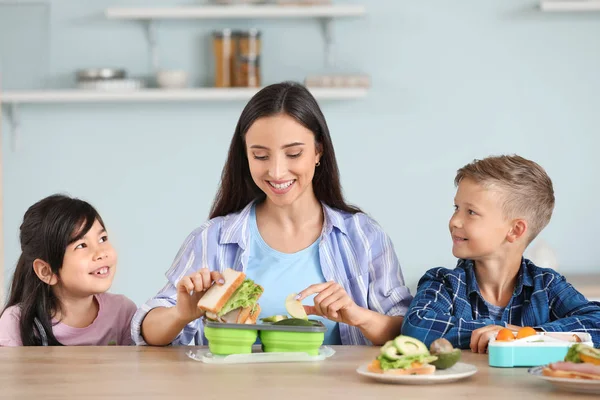 Mother packing school lunch for her little children at home — Stock Photo, Image