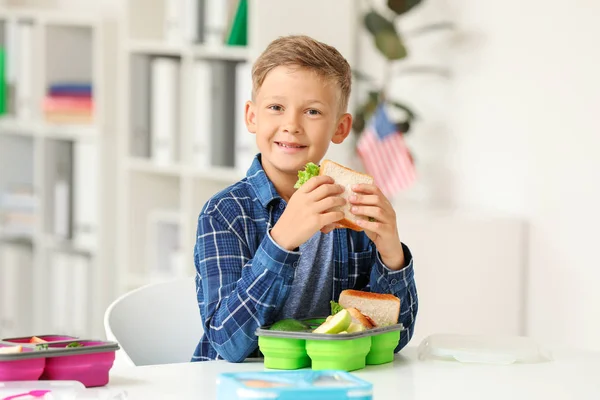 Little schoolboy eating tasty lunch in classroom — Stock Photo, Image