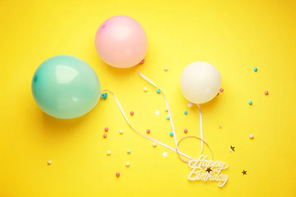 Balloons, decor and text HAPPY BIRTHDAY on color background