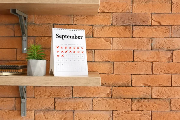 Estante con calendario de papel flip en la pared de ladrillo —  Fotos de Stock