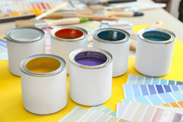 Cans of paints with palette samples on table