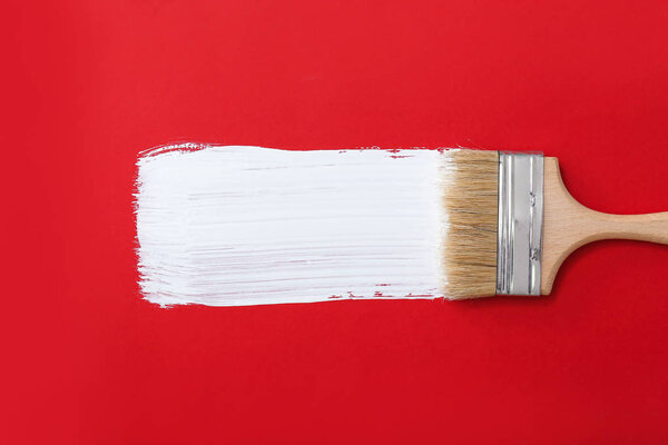 Кисть с мазком краски на цветном фоне
