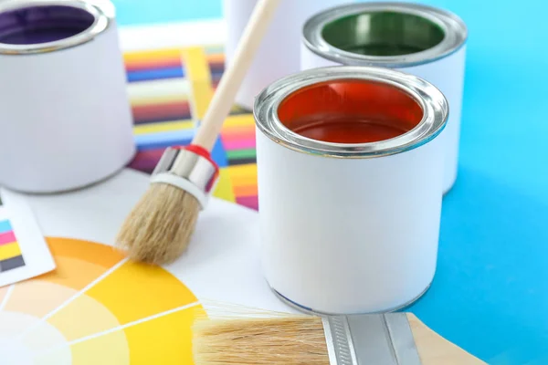 Банки фарб з пензлями та зразками палітри на кольоровому фоні — стокове фото
