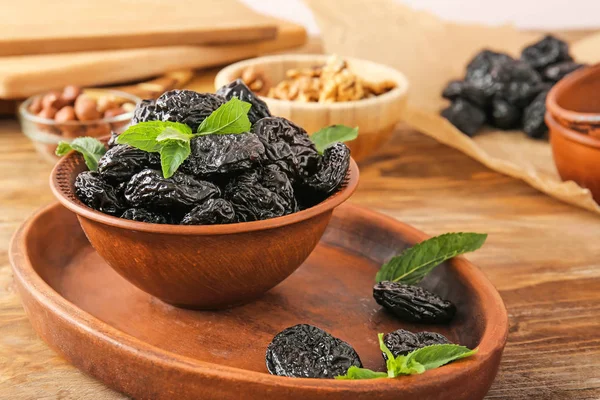Bowl and plate with tasty prunes on wooden table — Stock Photo, Image