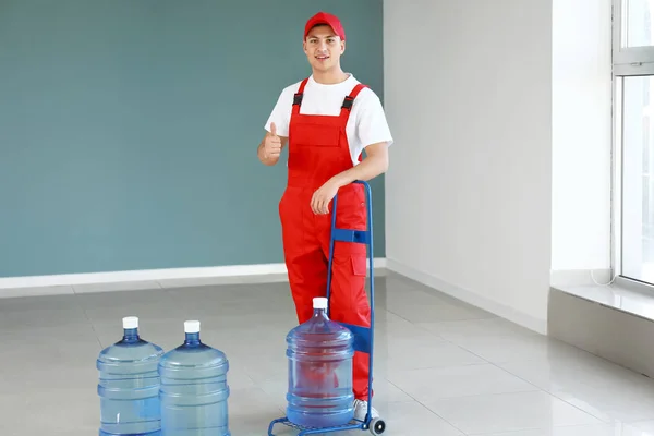 Entrega homem com garrafas de água dentro de casa — Fotografia de Stock