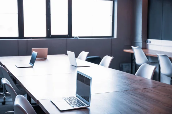 Gran mesa con ordenadores portátiles preparados para reuniones de negocios en la oficina moderna — Foto de Stock