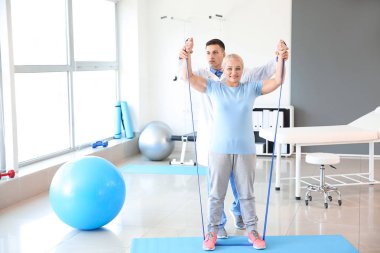 Rehabilitasyon merkezinde olgun hasta ile çalışan fizyoterapist