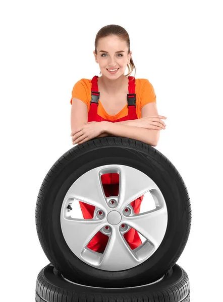 Jovem mecânica feminina em uniforme com pneus de carro no fundo branco — Fotografia de Stock
