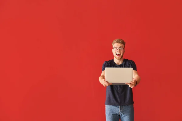 Happy young man with laptop on color background — Stock Photo, Image