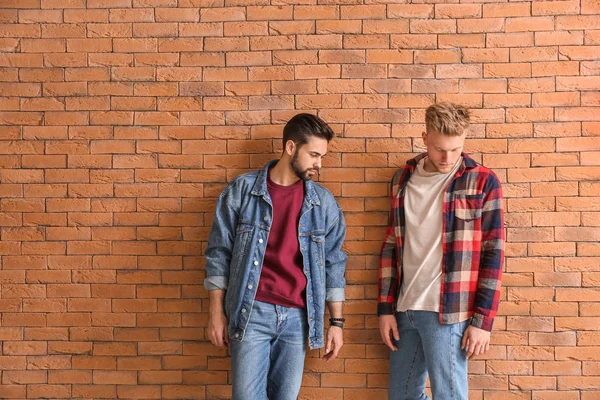 Модные юноши возле кирпичной стены — стоковое фото