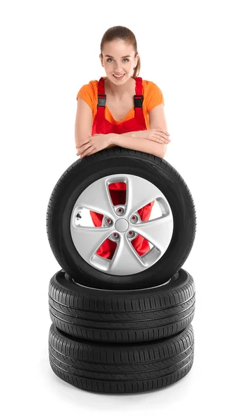 Jeune mécanicienne en uniforme avec des pneus de voiture sur fond blanc — Photo