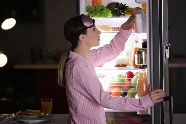Bella giovane donna che sceglie il cibo in frigorifero di notte — Foto Stock