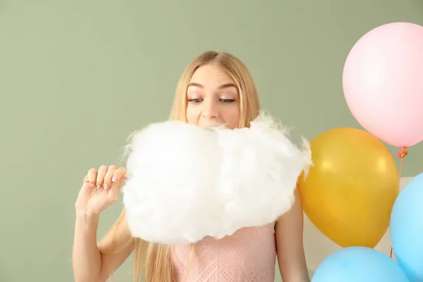 Hermosa mujer con algodón de azúcar y globos de aire sobre fondo de color —  Fotos de Stock