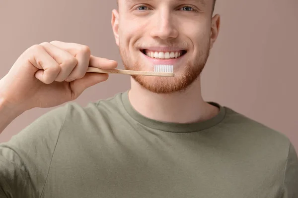 Jovem limpando os dentes no fundo da cor, close-up — Fotografia de Stock
