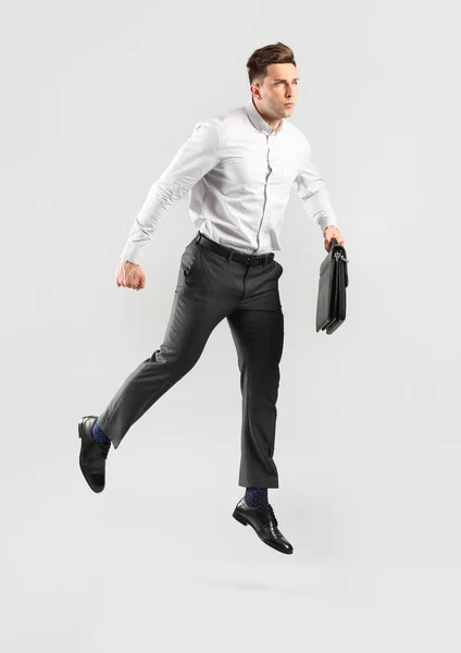 Jumping joven empresario sobre fondo gris —  Fotos de Stock