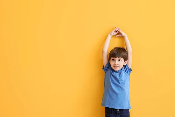 Aranyos kisfiú mérési magasság közelében színes fal — Stock Fotó