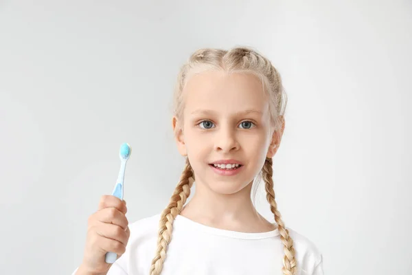 Little girl with toothbrush on light background — Stock Photo, Image