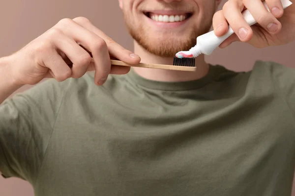 Young man cleaning teeth on color background, closeup — Stock Photo, Image