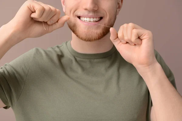 Junger Mann mit Zahnseide auf farbigem Hintergrund — Stockfoto