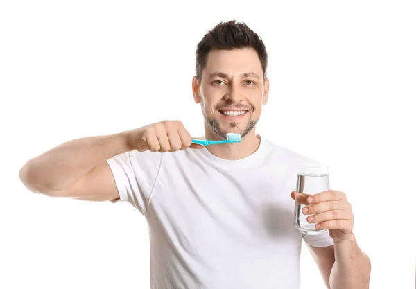 Man with toothbrush and glass of water on white background — Stock Photo, Image