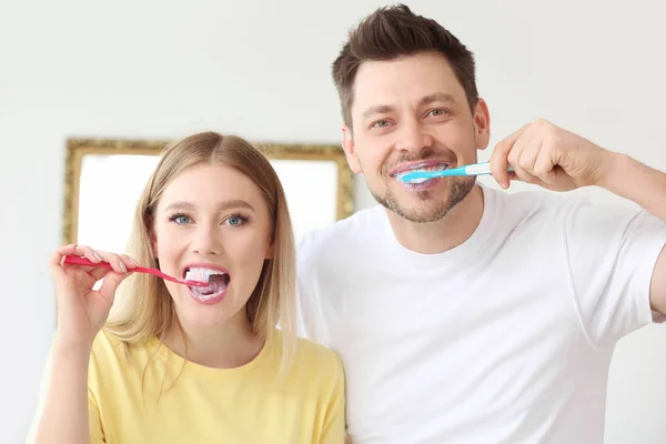 Happy couple cleaning teeth at home