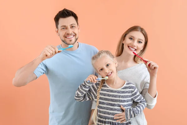 Family cleaning teeth on color background