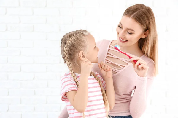 Vrouw en haar kleine dochter het schoonmaken van tanden op witte achtergrond — Stockfoto