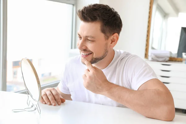Человек со здоровыми зубами смотрит в зеркало дома — стоковое фото