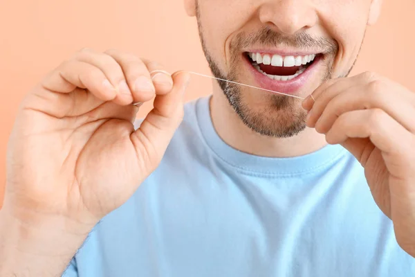 Hombre dientes de hilo dental en el fondo de color, primer plano — Foto de Stock