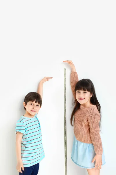 Cute little children measuring height near wall — Stock Photo, Image