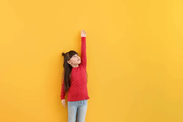 컬러 벽 근처 높이 측정 하는 귀여운 어린 소녀 — 스톡 사진