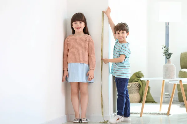 Cute little children measuring height near wall — Stock Photo, Image