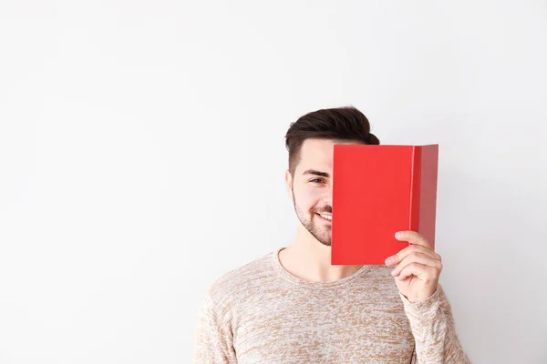 Pohledný mladý muž s knihou na pozadí — Stock fotografie