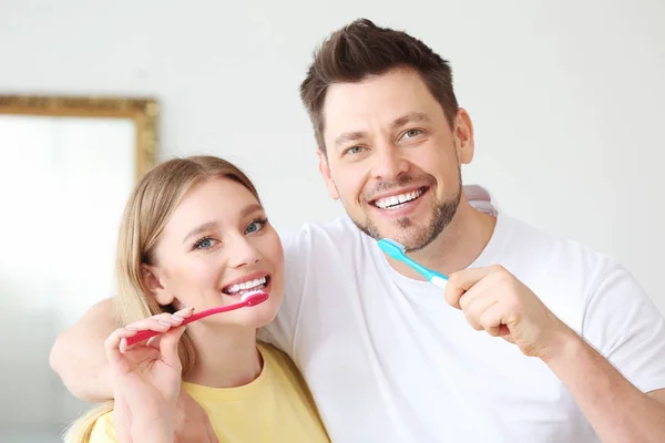 Happy couple cleaning teeth at home