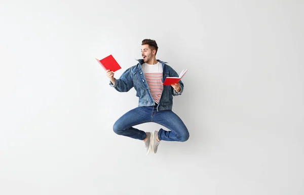 Junger Mann mit Büchern auf hellem Hintergrund — Stockfoto