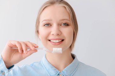 Hafif arka planda diş fırçası olan bir kadın. Diş hijyeni konsepti