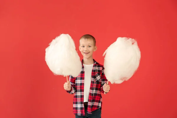 Cute little boy with cotton candy on color background — Stock Photo, Image