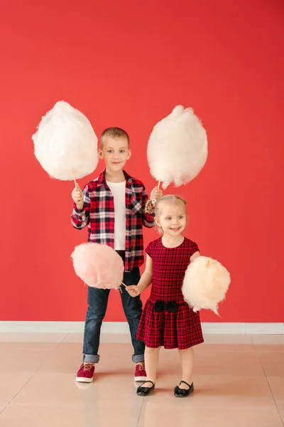 Cute little children with cotton candy against color wall — Stock Photo, Image