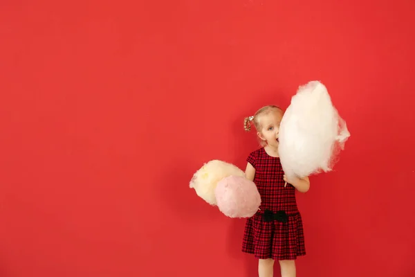 Niedliches kleines Mädchen mit Zuckerwatte auf farbigem Hintergrund — Stockfoto