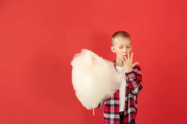 Cute little boy with cotton candy on color background — Stock Photo, Image