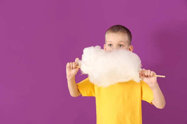Милый маленький мальчик с сахарной ватой на цветном фоне — стоковое фото