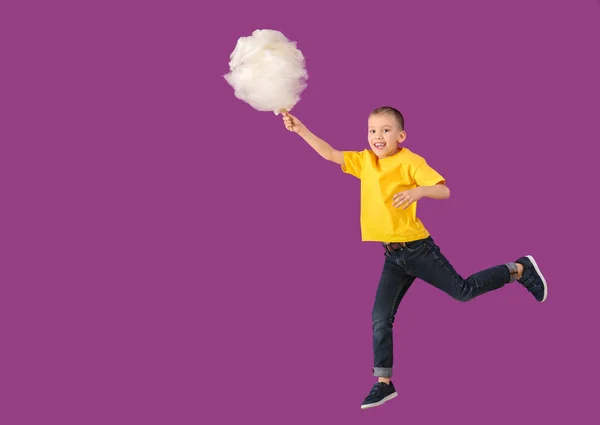 Jumping little boy with cotton candy on color background — Stock Photo, Image