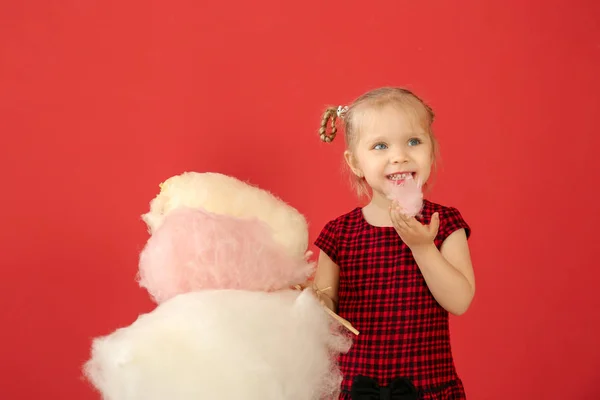 Cute little girl with cotton candy on color background — Stock Photo, Image