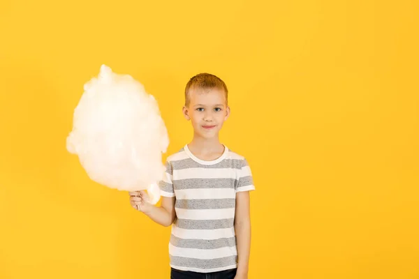 Menino bonito com algodão doce no fundo de cor — Fotografia de Stock