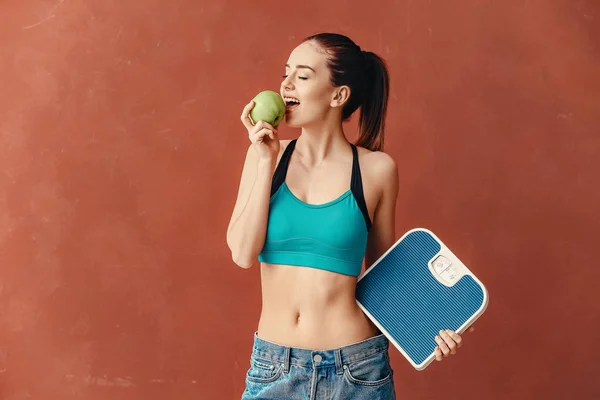 Mujer joven con escamas y manzana sobre fondo de color. Concepto de pérdida de peso — Foto de Stock