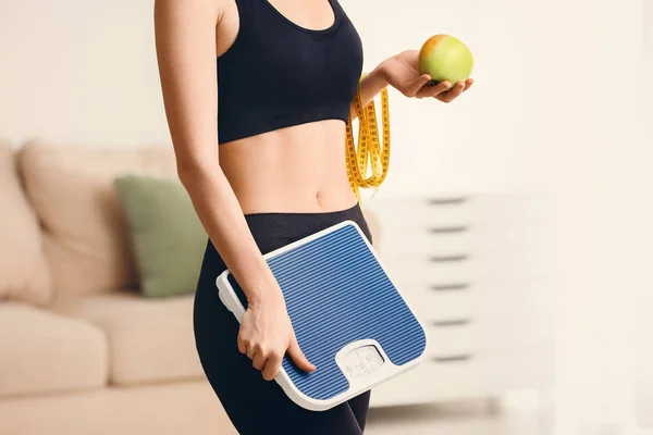 Woman with measuring tape, scales and apple at home. Weight loss concept — Stock Photo, Image