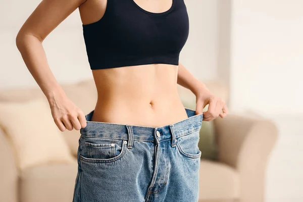 Woman in loose jeans at home. Weight loss concept — Stock Photo, Image