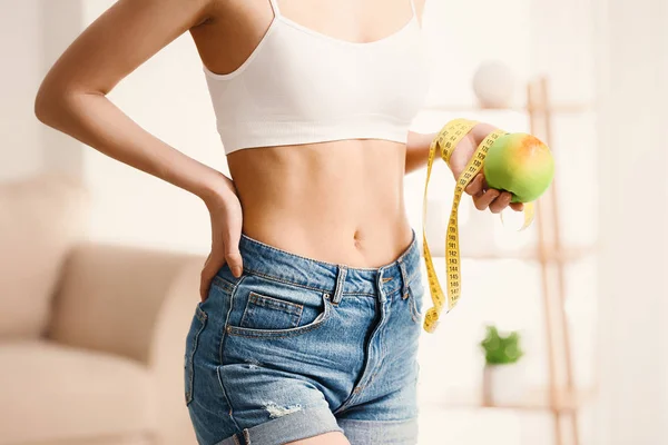 Mujer con cinta métrica y manzana en casa. Concepto de pérdida de peso — Foto de Stock