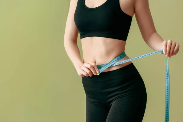 Mujer joven con cinta métrica sobre fondo de color. Concepto de pérdida de peso — Foto de Stock