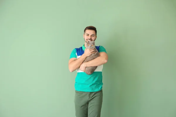 Hombre joven con lindo gato divertido en el fondo de color —  Fotos de Stock